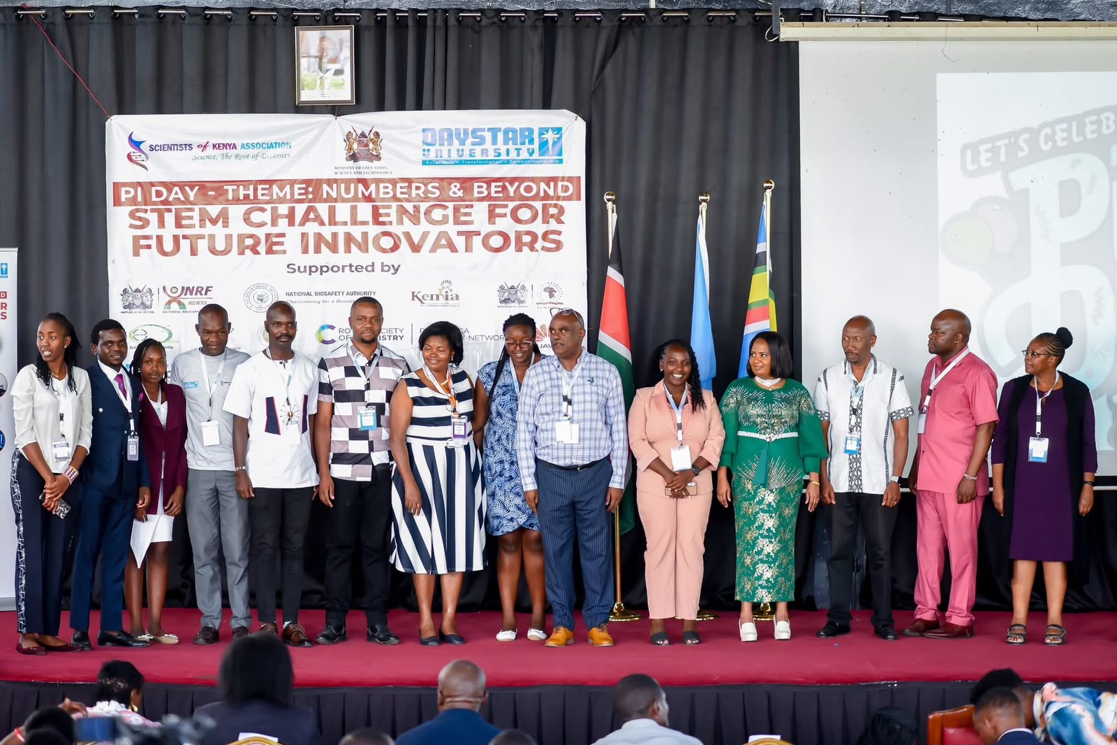 SCOKA leaders and partners on stage at Pi Day STEM Challenge — Numbers & Beyond, with Ministry of Education and Daystar University banners